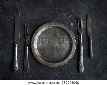 Vintage kitchen utensils on a background of black stone, plate, knife and fork