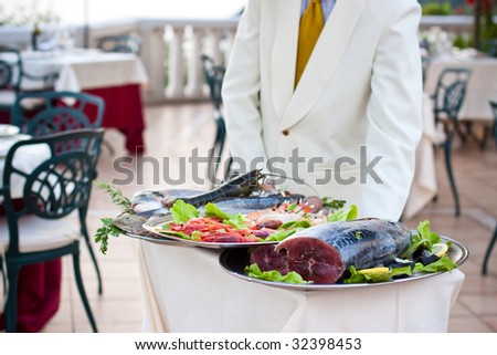 The waiter showing to the guests the fresh fish of the day. Lobster, king prawns, scampi, amber jack, sea bass and all the other kinds of the italian fish tradition