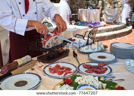 Italian Chef cutting Parma raw ham at wedding buffet