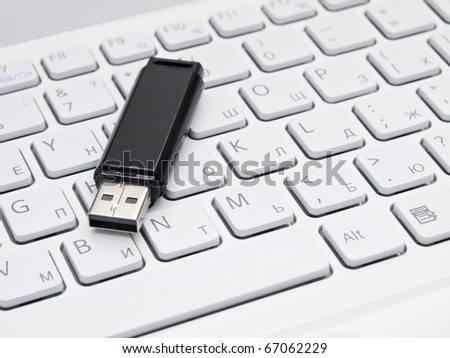 Black flash drive on white keyboard.