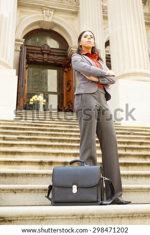 Serious legal or business woman on steps with arms crossed looking forward.