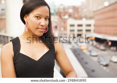 A young woman with a cityscape backdrop looks at the viewer.