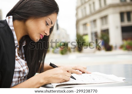 A seated woman looking through the job listings in a newspaper. She could also be looking at real estate listings.