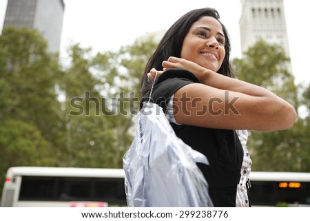 An attractive woman carrying a professionally laundered shirt over her shoulder.