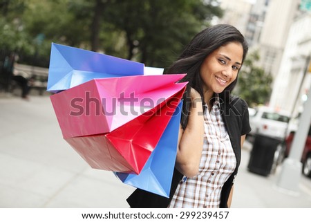 Young woman holding shopping bags over her shoulder and smiling at viewer.