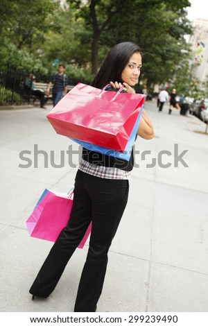 A woman with shopping bags looking back over her shoulder.