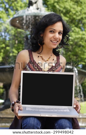 Woman holding blank laptop screen to viewer.