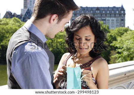 Woman peers into gift bag from man.
