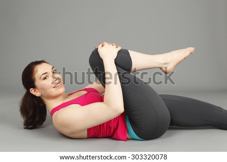 A young woman lying on her back stretching her leg.