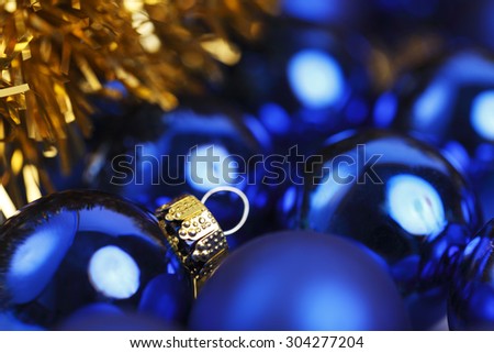 Close-up of blue Christmas Balls and gold garland. Focus is on gold cap of Christmas Ball.