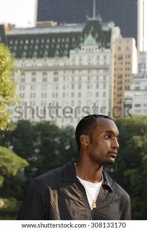 Young man in profile with cityscape background in Central Park.