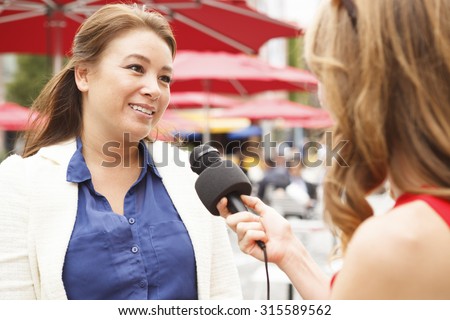 A woman being interviewed outdoors.