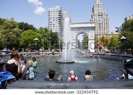 New York, New York, USA - July 14, 2011: Adults relax and children play in and around the fountain in Washington Square Park on a hot summer day in Greenwich Village, Manhattan.