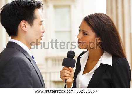A woman with a microphone interviews a well dressed man. Could be politician, business or other professional.
