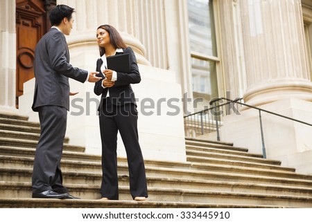Professional woman and man having a discussion on the stairs of a stately building. Could be lawyers, business people etc.