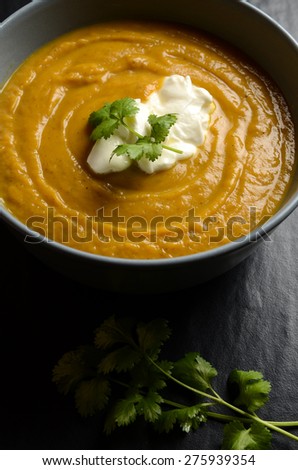 Bowl of fresh homemade sweet potato soup with ricotta cheese and coriander leaves