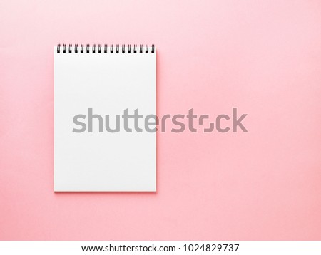 Blank notepad white page on pink desk, color background. Top view,  empty space for text.