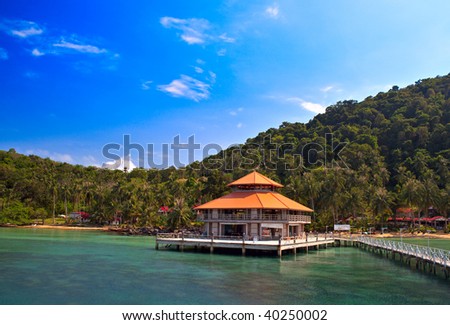 House on the sea water and pier with palms tree wood background, mountain and sky