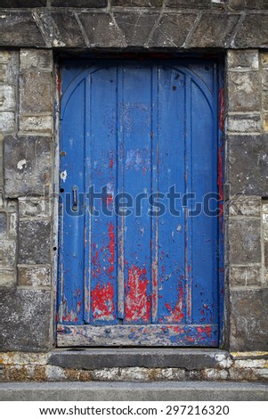 Red Door Painted Blue\
A once red door, painted blue is now peeling back to the original color, The colorful door is surrounded by heavy dark stonework.
