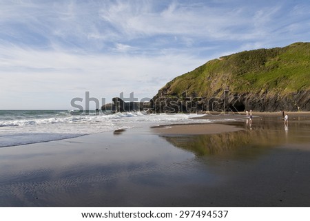 Welsh Beach,\
Llangrannog Beach in Wales late in the day near the longest day of the year. A low angle shot from the wet sand in the foreground through to the the far distant headland on the coastline.
