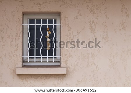 Window on a Beach Side cottage. A quirky grill and a hanging set of shells decorate a window on a seaside cottage in France.