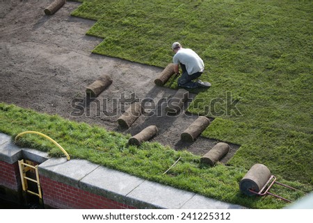 CIRCA SEPTEMBER 2014 - BERLIN: worker/ gardenere who rolls out lawn in a public park in Berlin.