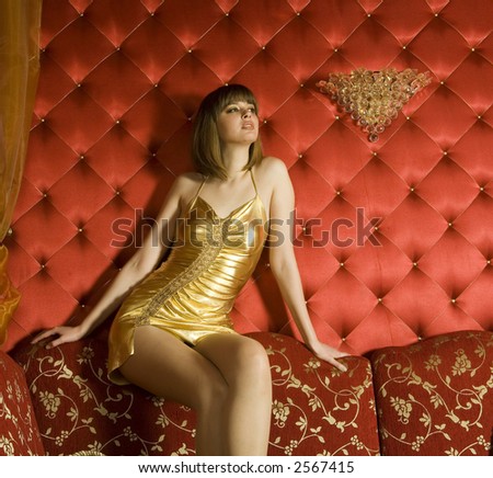 stock photo : Portrait of woman in gold dress on the red couch