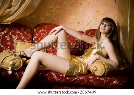 stock photo : Portrait of woman in gold dress on the red couch