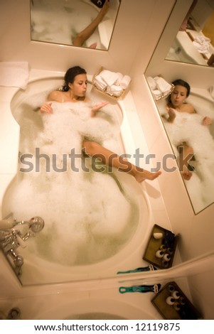 Young woman enjoys the bath-foam in the bathtub.