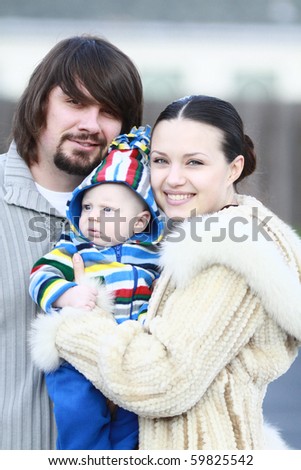 Portrait of a young and happy family outdoors. Young lovely couple outdoor holding new born baby and smiling in to the camera. blurry background.
