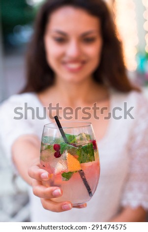beautiful smiling woman drinking cold lemonade berry,  in a summer cafe. selective Focus
