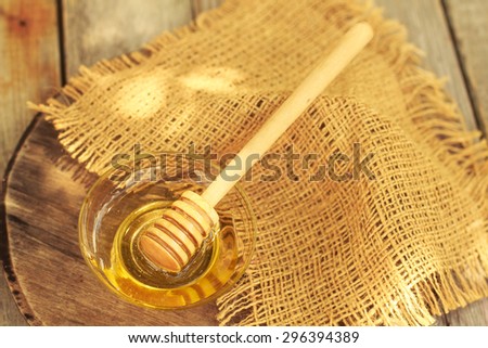 Honey dripping from a wooden honey dipper on natural background