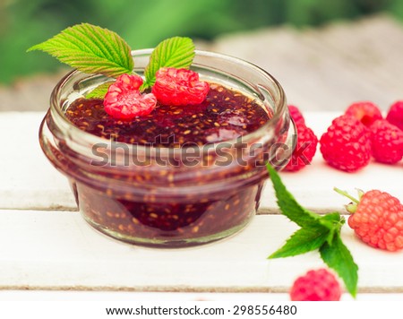Raspberry jam ( marmalade ) in a jar and fresh raspberry on a rustic wooden table.Selective focus.