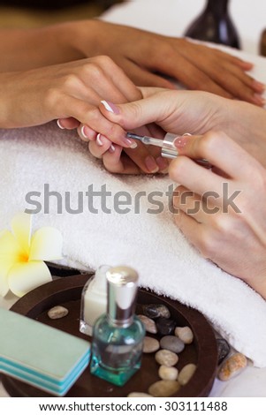 Woman in nail salon receiving manicure by beautician. closeup of female hand resting on white towel