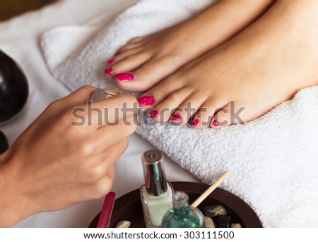 Woman in nail salon receiving pedicure by beautician. closeup of female hand resting on white towel