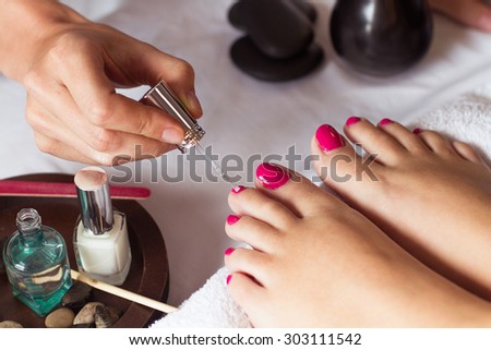 Woman in nail salon receiving pedicure by beautician. closeup of female hand resting on white towel