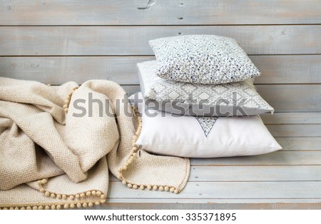 Cushions and plaid on the white wooden background closeup.