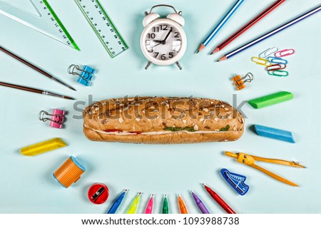 Back to school concept. school snack sandwich and school supplies on blue background. Flat lay stylish set top view. copy space.
