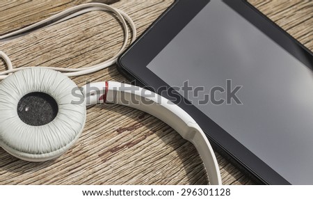 Black and White tablet and headphones on a wooden background