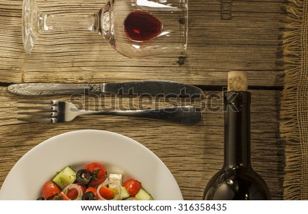 Wine.  Thanksgiving Day. glass of wine and a bottle. Small plate Greek salad on a wooden table. CLOSE-UP.