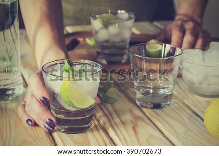A young girl is preparing an alcoholic or non-alcoholic cocktail. hands, bartender, bar, restaurant, mint, lime, lemon, alcoholic, non-alcoholic