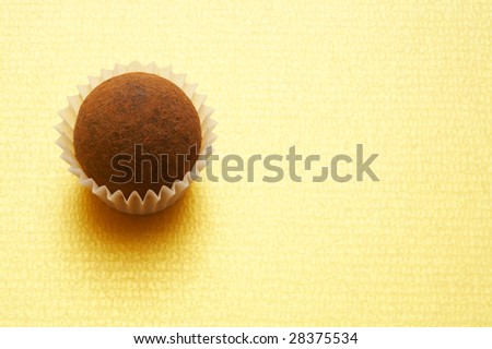 A chocolate truffle on gold background in the left