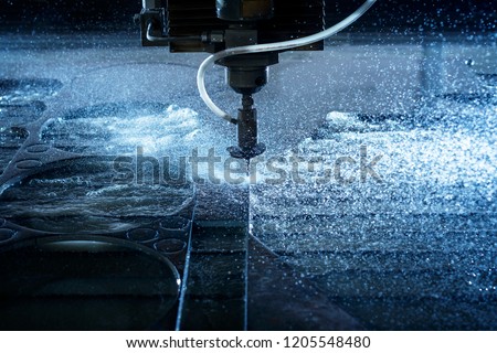 Water jet industrial machine cutting steel plate. Computer controlled metalworking machine using high pressure water jet to cut metal.
