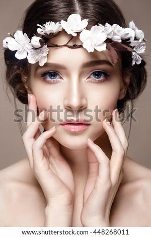 Beautiful woman portrait in tender colors. Young lady posing in studio with flowers on head. Pure skin, nice make up.