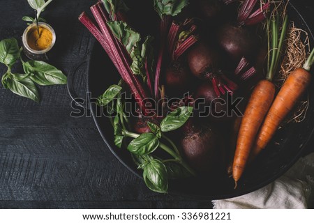 Bunch of young onions , beets, carrots and basil on a black background of the old wooden boards vintage top view