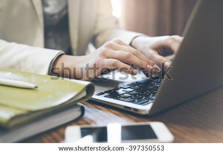Young woman writes hands a text message on laptop keyboard with a empty blank screen monitor while having recreation time at home, person with a cup of coffee against a background of bokeh in cafe