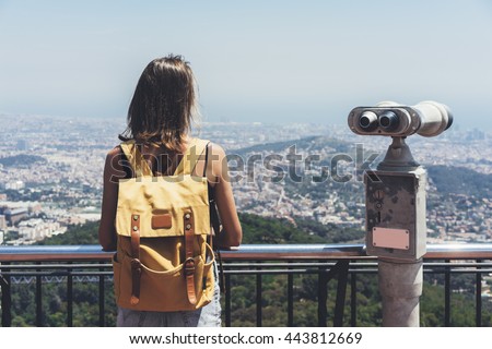 Hipster young girl with bright backpack looking on observation deck and travel plan. Tourist traveler background panoramic view of city, coin binoculars. Mock up for text message. Barcelona Tibidabo