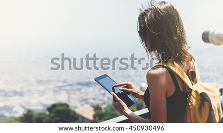 Hipster young girl with  backpack. Tourist traveler on background panoramic view of the city, coin binoculars. Mock up for text message. Barcelona Tibidabo. Female hands using tablet, holding gadget