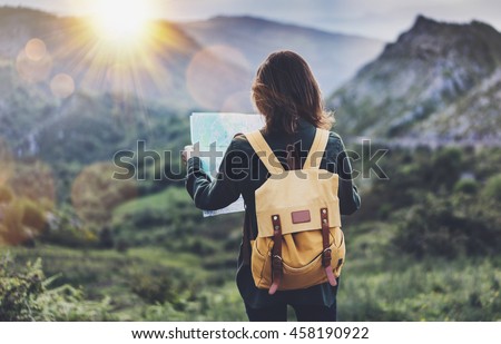 Hipster young girl with backpack enjoying sunset on peak of foggy mountain, looking a map. Tourist traveler on background landscape panoramic view mockup, flare in trip Spain basque country, mock up