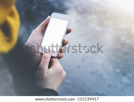 Hipster girl texting message on smartphone mobile in winter nature, view tourist hands using gadget phone on background blue ice and freeze; finger touch screen blank cellphone mockup, templates